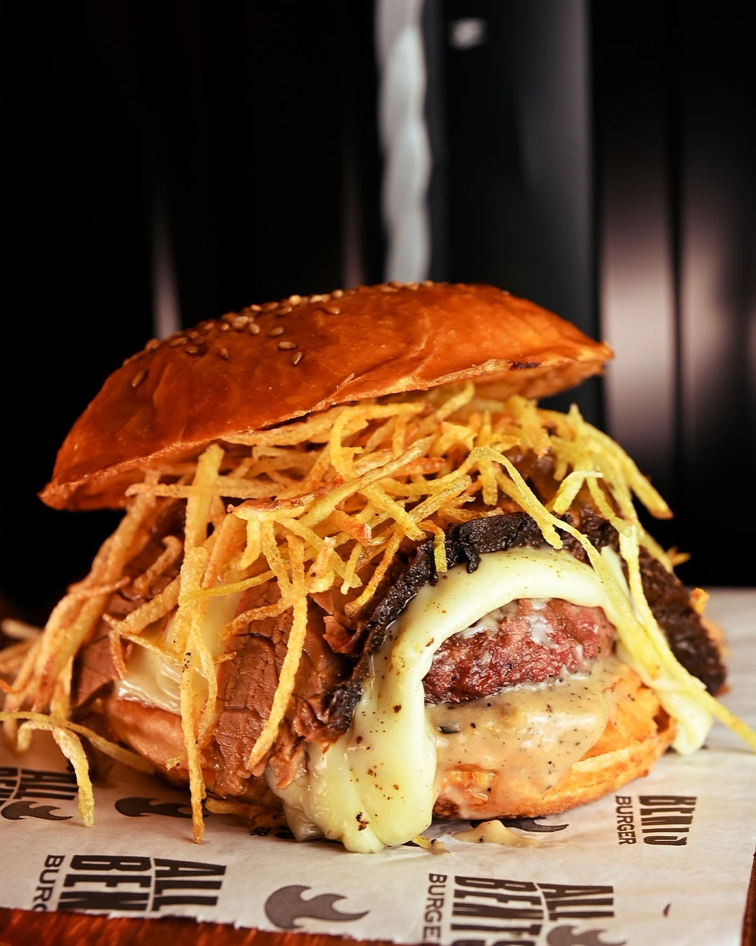 Minas Texas Burger em close, com queijo derretido e uma generosa camada de batata palha